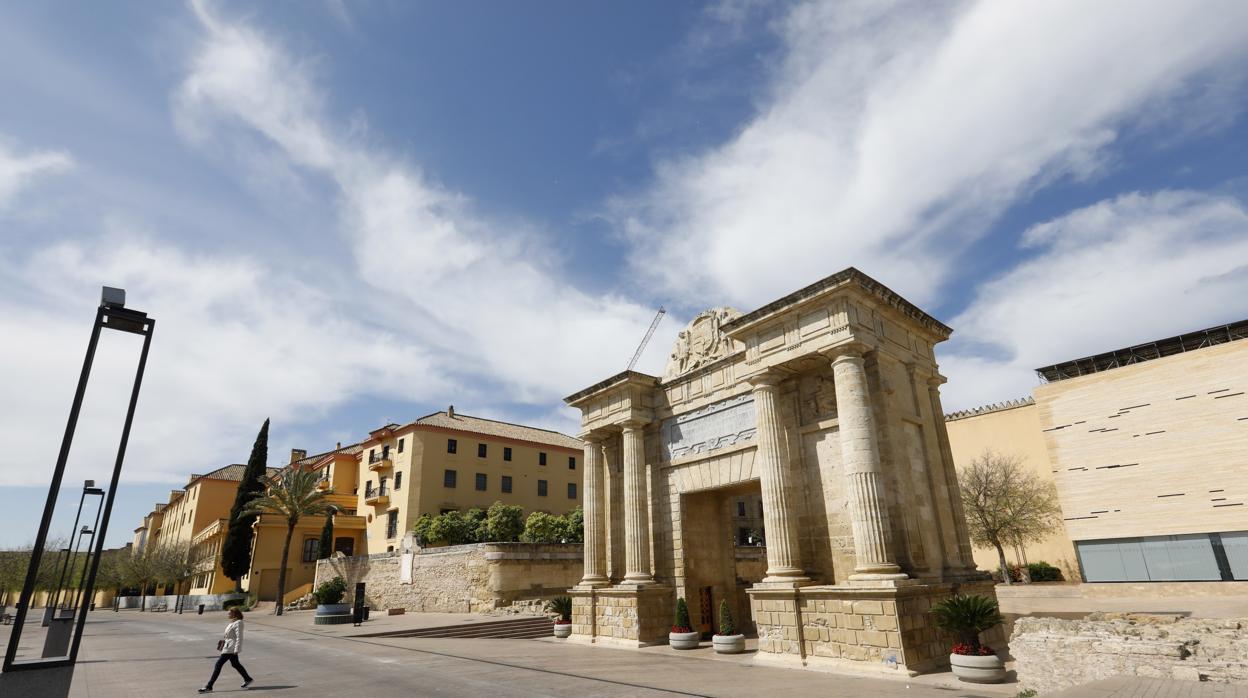 Una mujer cruza hacia el Puente Romano desde la Puerta de Felipe II