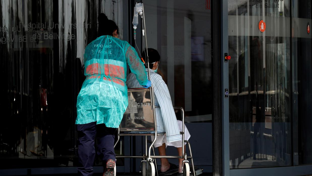 Una auxiliar sanitaria asiste a un paciente a la entrada de un hospital