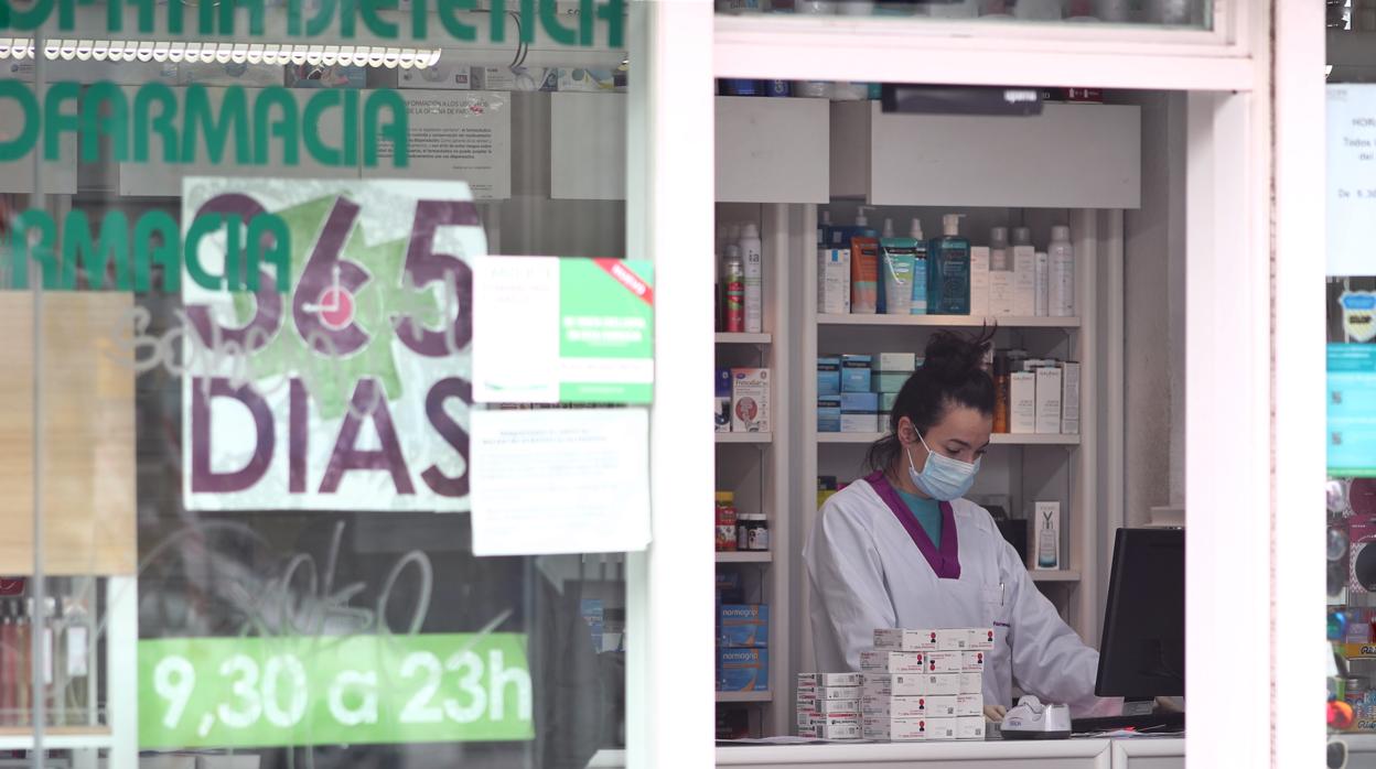 Imagen de una farmacia donde se protegen con una mascarilla mientras atienden