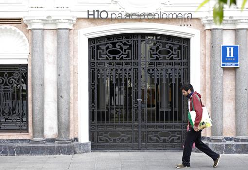 Un joven pasa delante de la puerta cerrada del Hotel Palacio Colomera