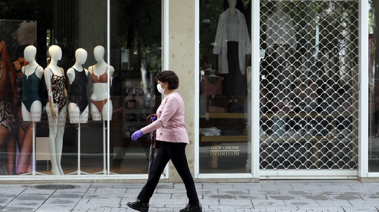 Una mujer camina junto a locales cerrados