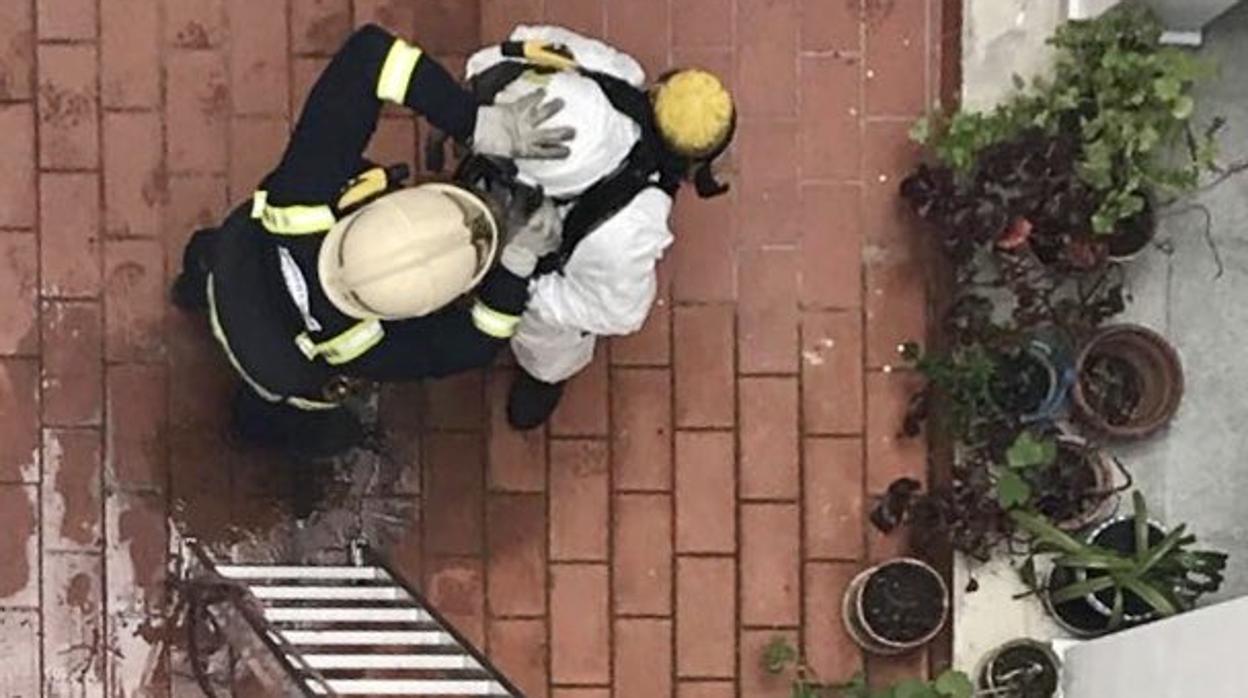 Un bombero se equipa para acceder a la vivienda donde ha sido hallado un hombre muerto