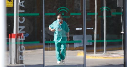 Un médico reflejado en la puerta de Urgencias