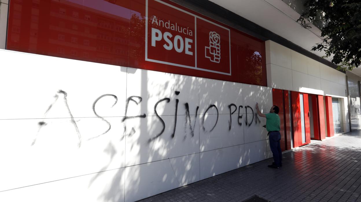 Un operario retira la pintada de la sede del PSOE en la mañana del domingo