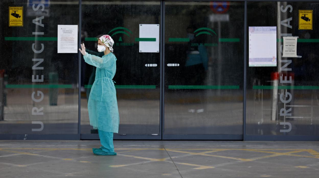 Una profesional sanitaria despide a una ambulancia con un paciente en el Reina Sofía de Córdoba