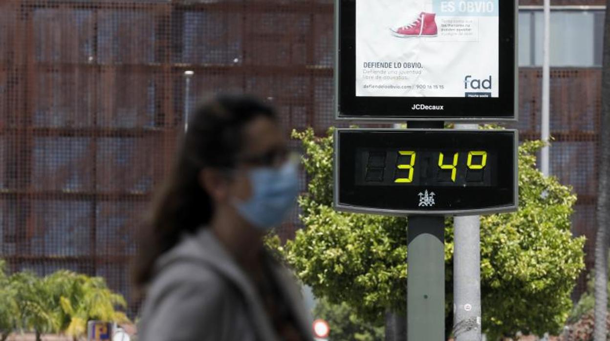 Una mujer pasa por delante de un termómetro urbano durante la crisis del coronavirus