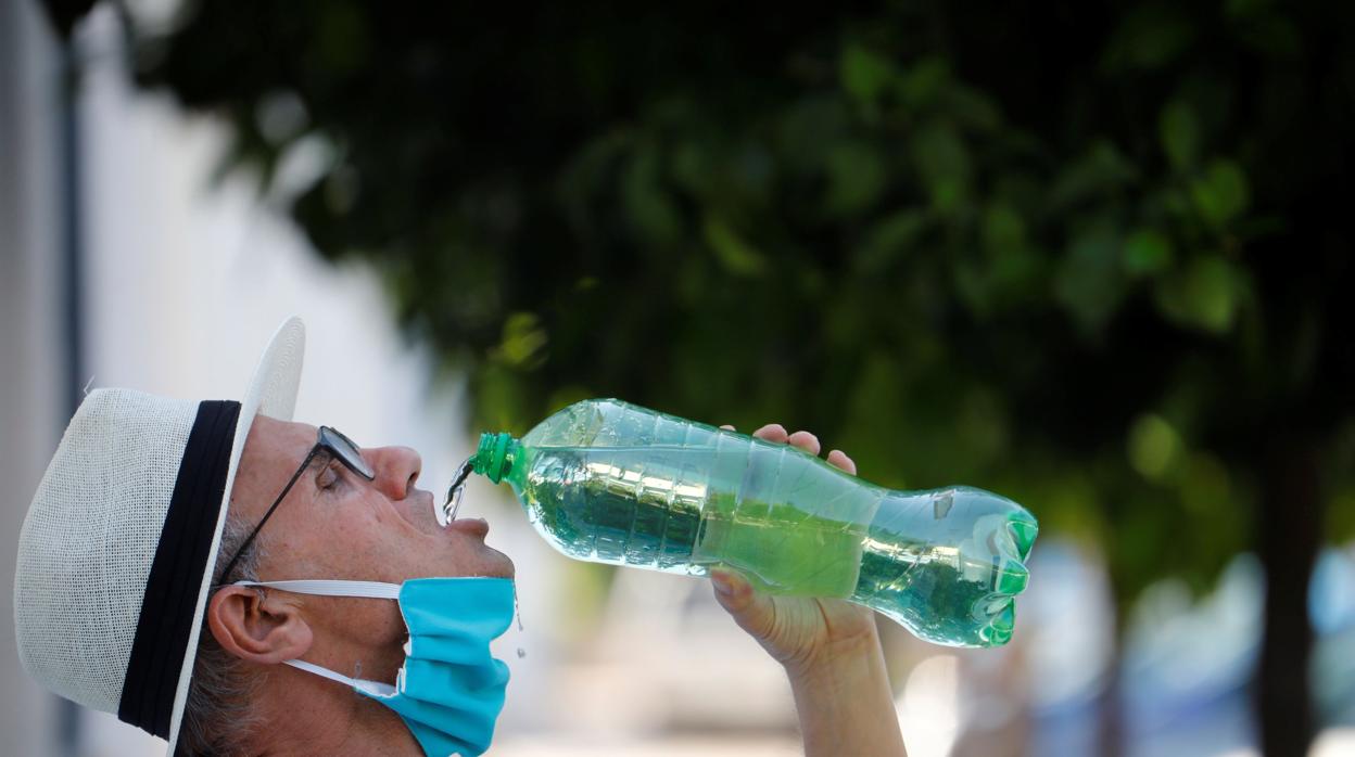 Un hombre se refresca en plena calle tras haberse quitado la mascarilla