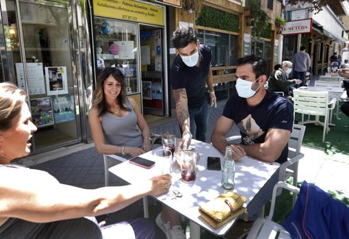 Un camarero atiende a unos clientes en una terraza de Doce de Octubre