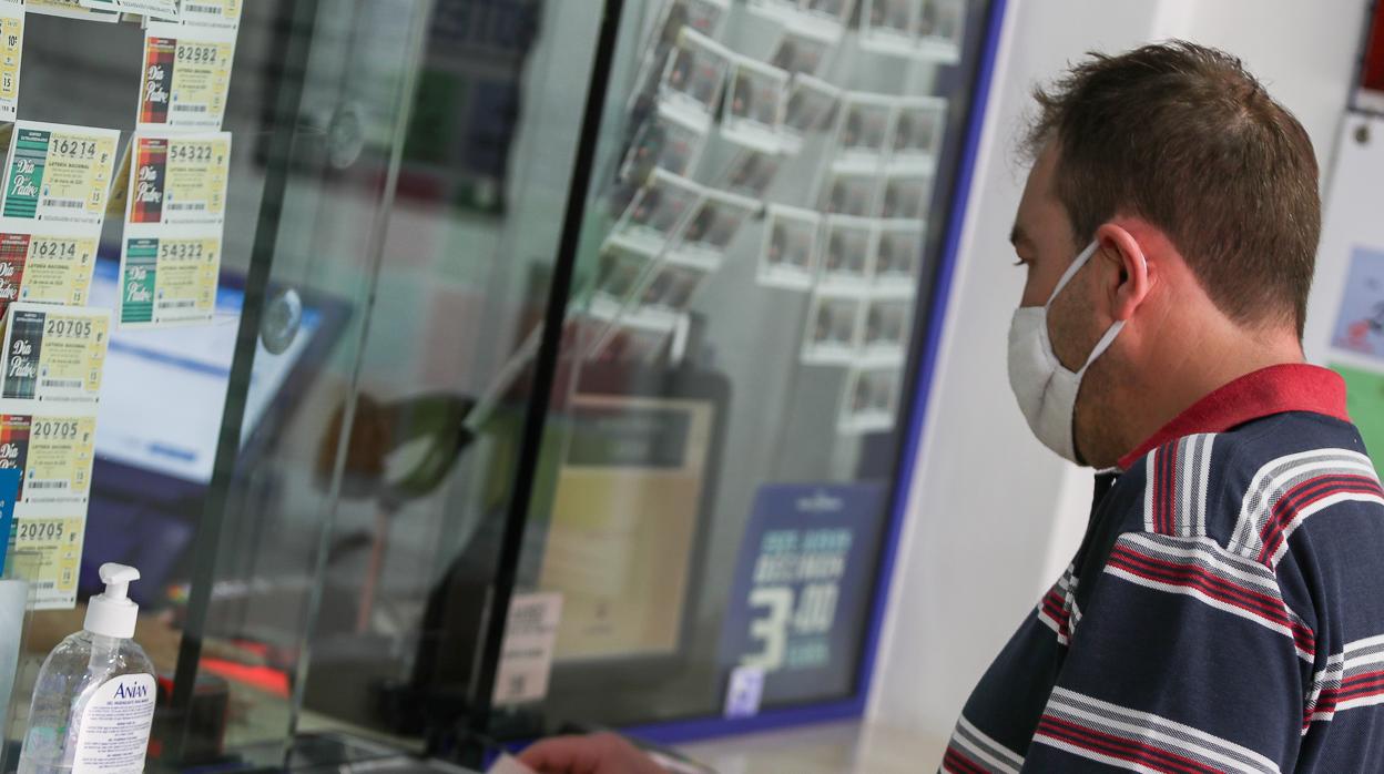 Un hombre con mascarilla en el itnerior de una administración lotera