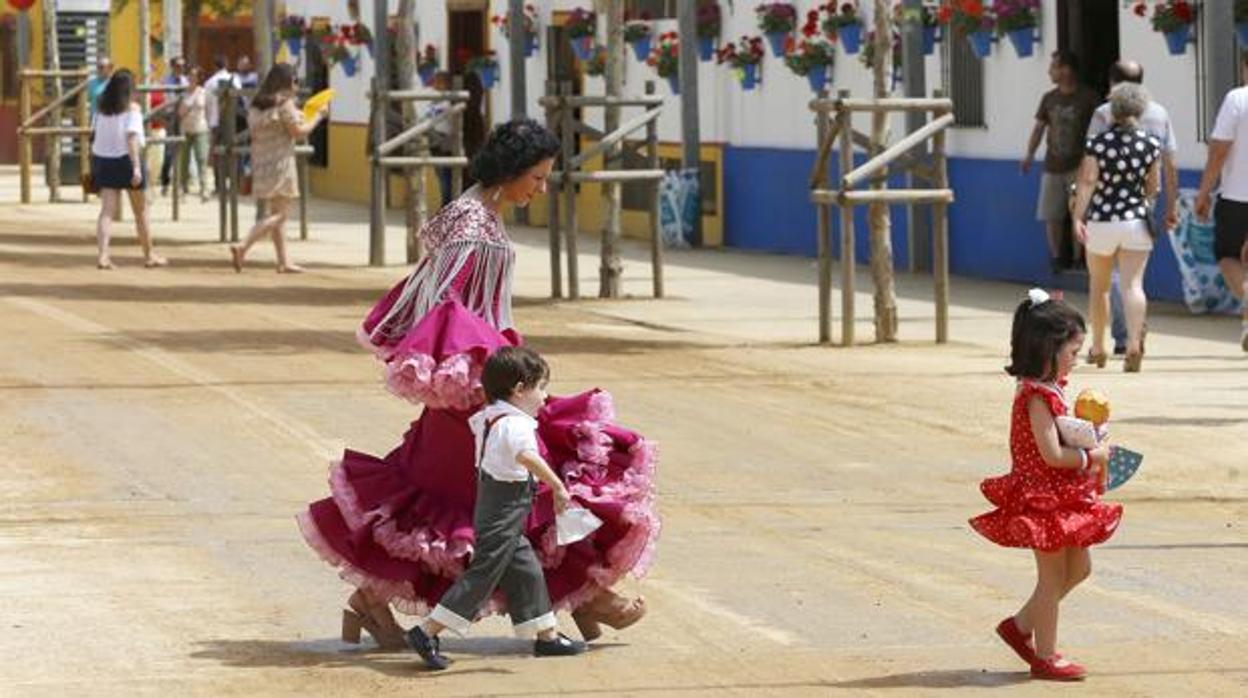 Una cordobesa vestida de flamenca en la Feria con dos niños pequeños en una foto de archivo