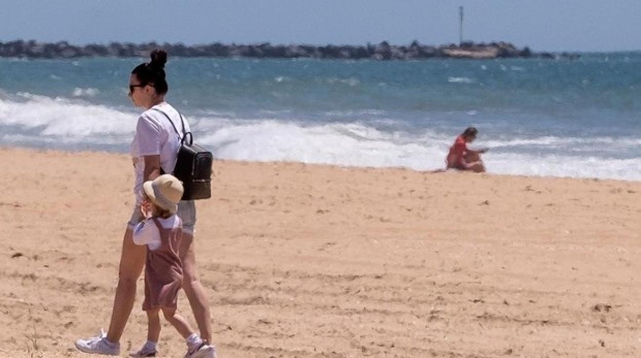 Una madre con su hija paseando por la playa