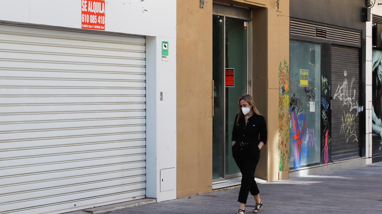 Una mujer pasa delante de tres locales comerciales de Cruz Conde que están en alquiler