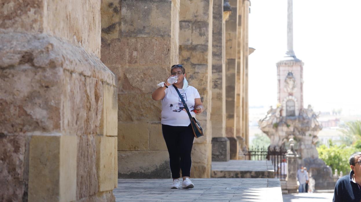 Una mujer bebe hoy agua para alivar el calor junto a la Mezquita-Catedral