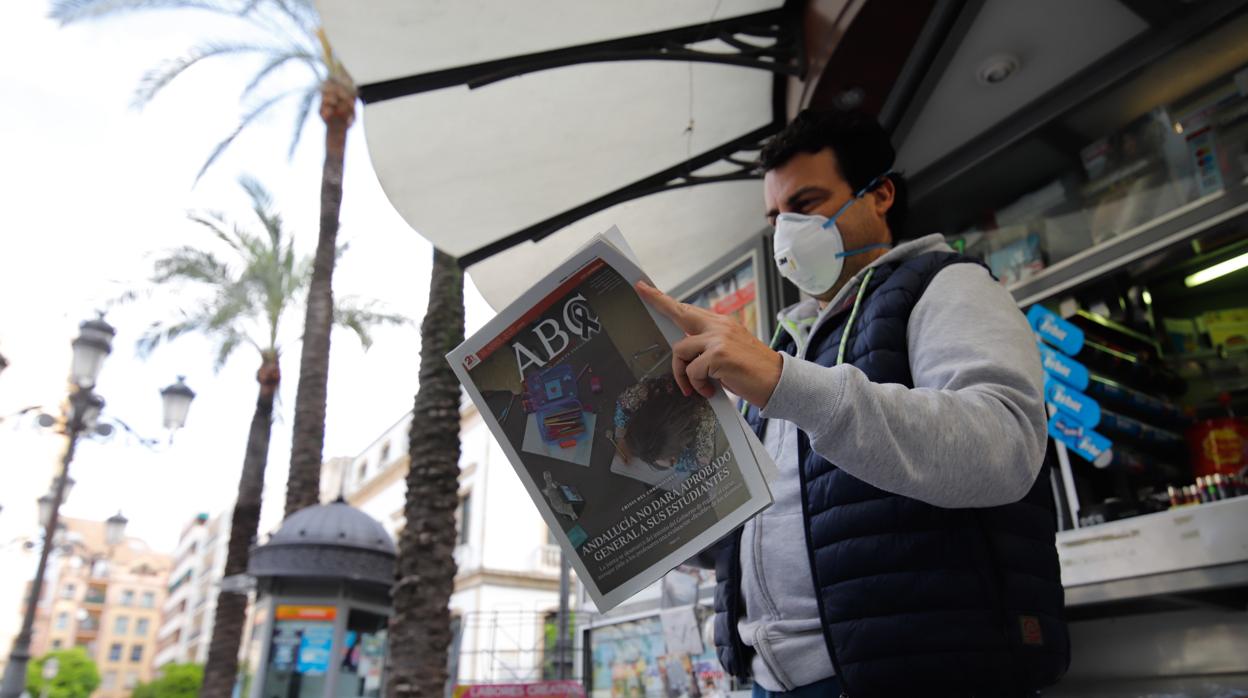 Un hombre lee un ejemplar de ABC Córdoba tras comprarlo en un quiosco