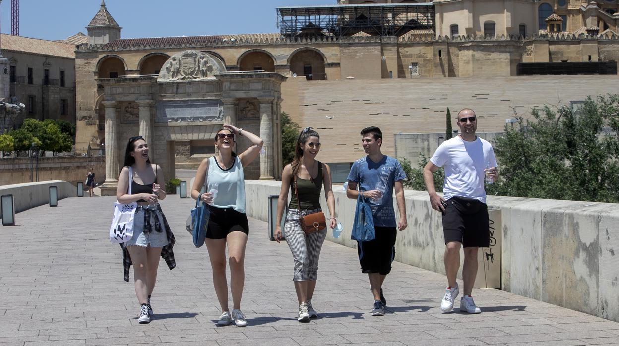 Un grupo de jóvenes pasea por el Puente Romano este junio en Córdoba