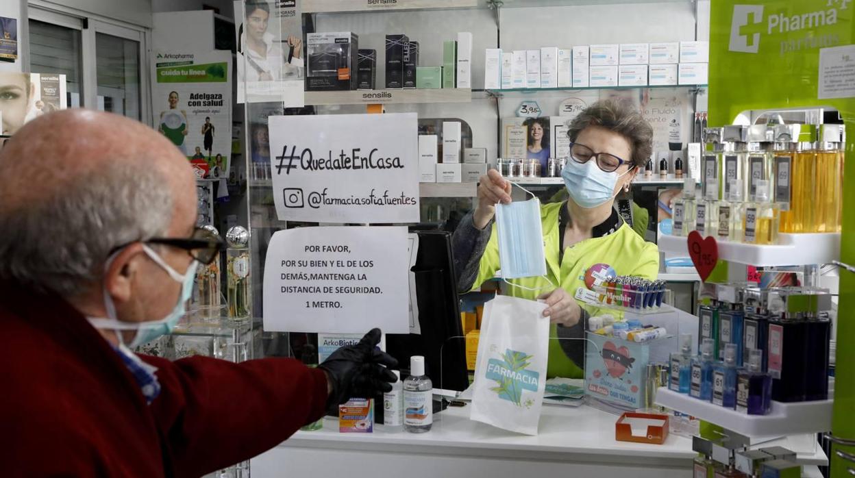 Una farmacéutica vendiendo una mascarilla a un cliente