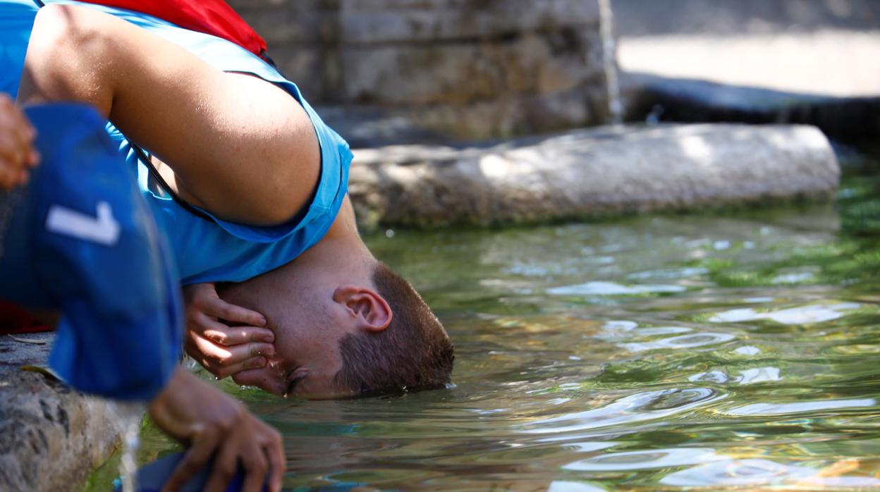 Un joven se refresca del calor en una fuente