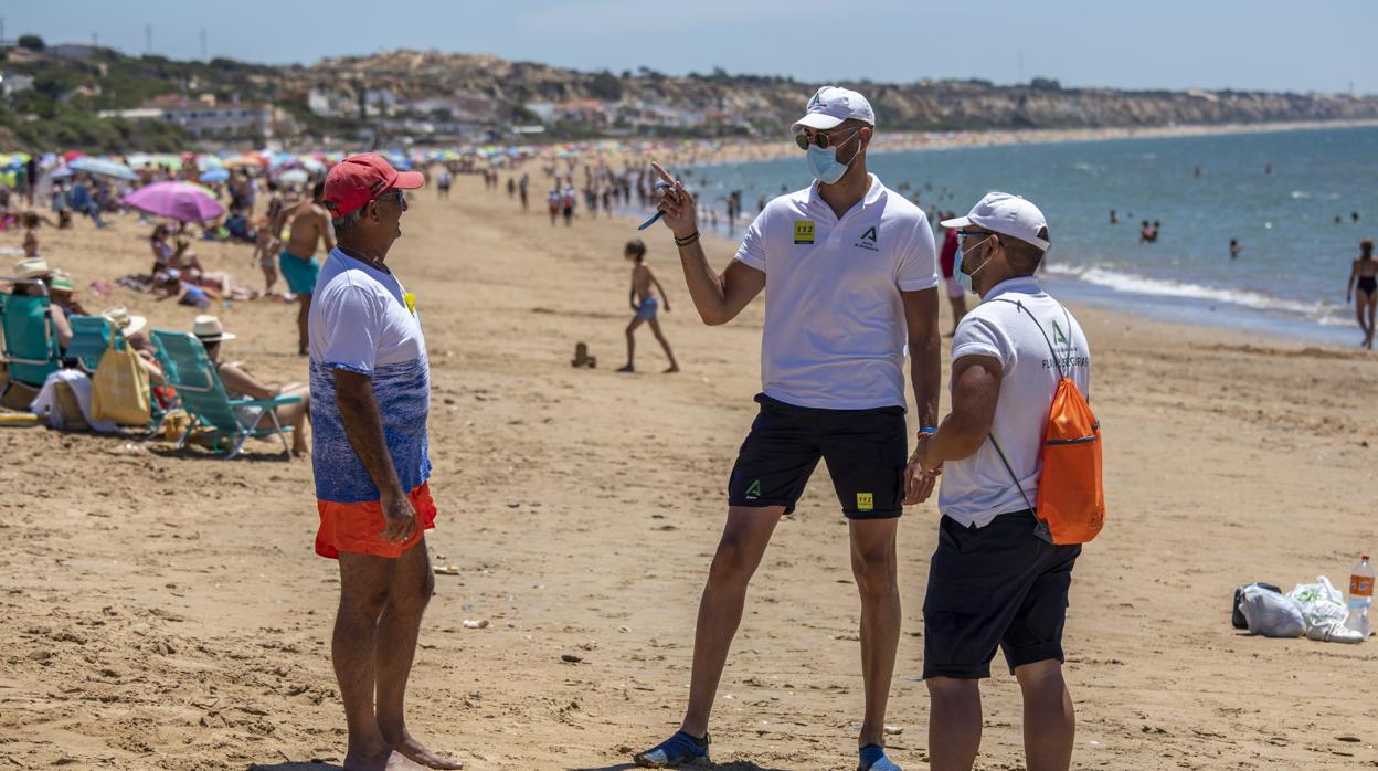 Dos vigilantes informando a un usuario en la playa de Mazagón