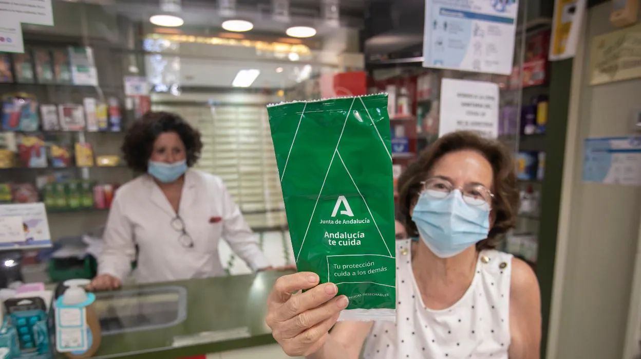 Una mujer muestra las mascarillas retiradas de una farmacia de Córdoba