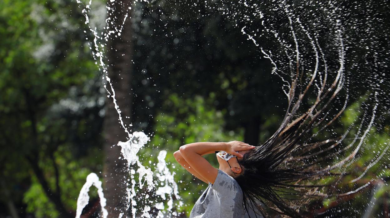 Una chica se refresca en Córdoba en una fuente pública