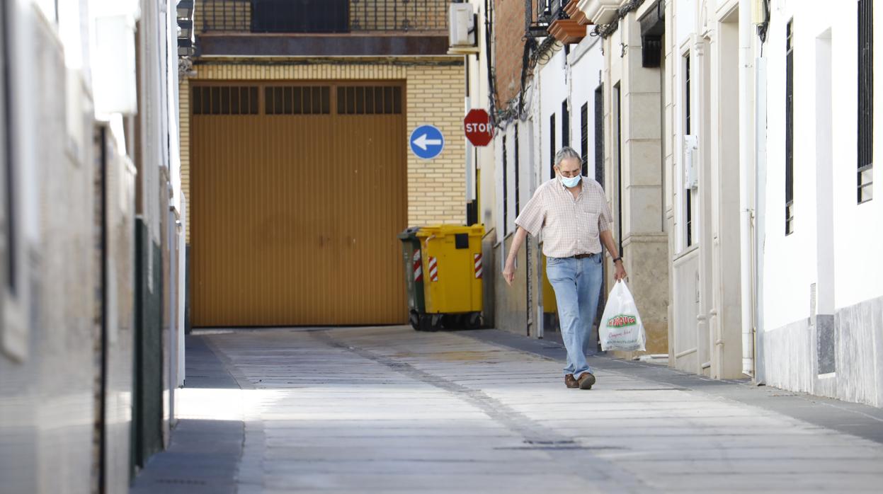 Un vecino regresa a casa por las calles vacías tras hacer la compra