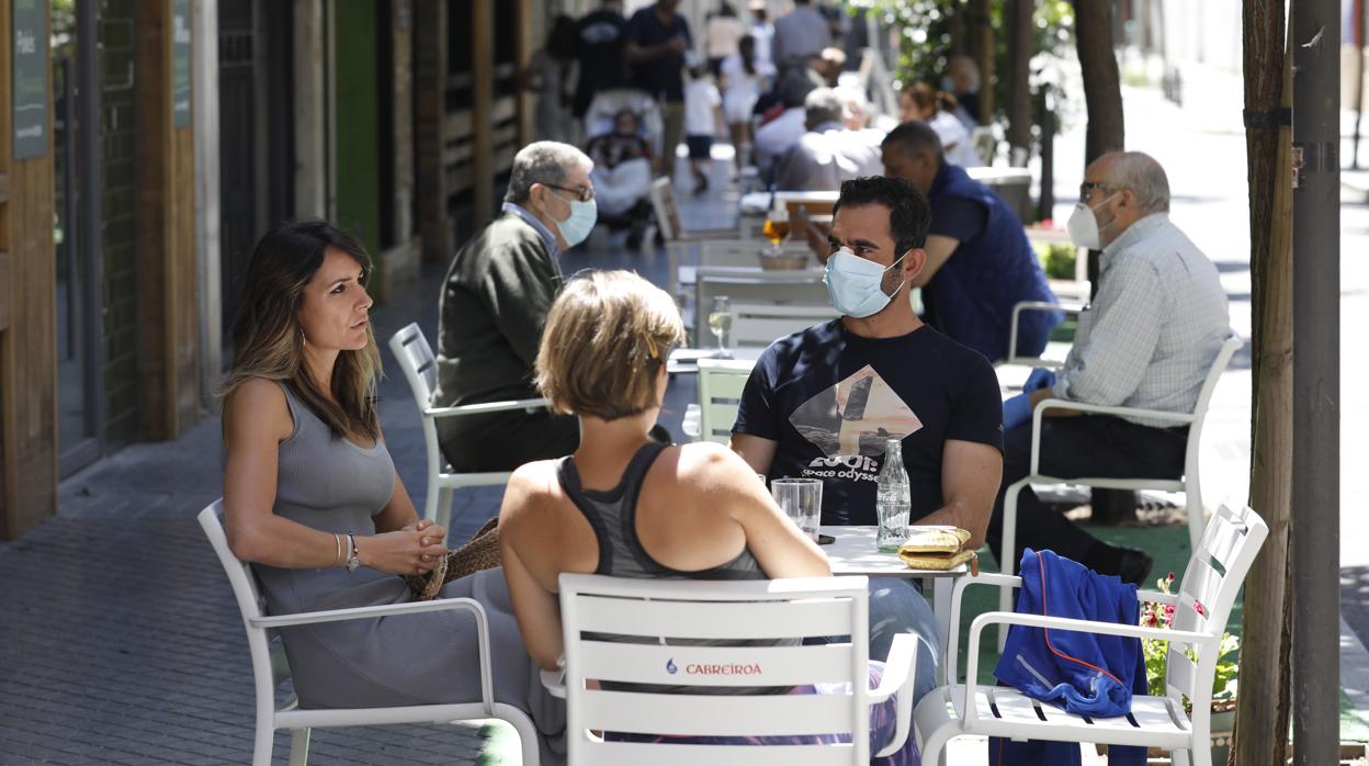 Varias personas se relajan tomando algo en los veladores de la calle Doce de Octubre