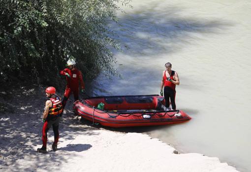 Varios bomberos junto a una lancha en el Guadalquivir