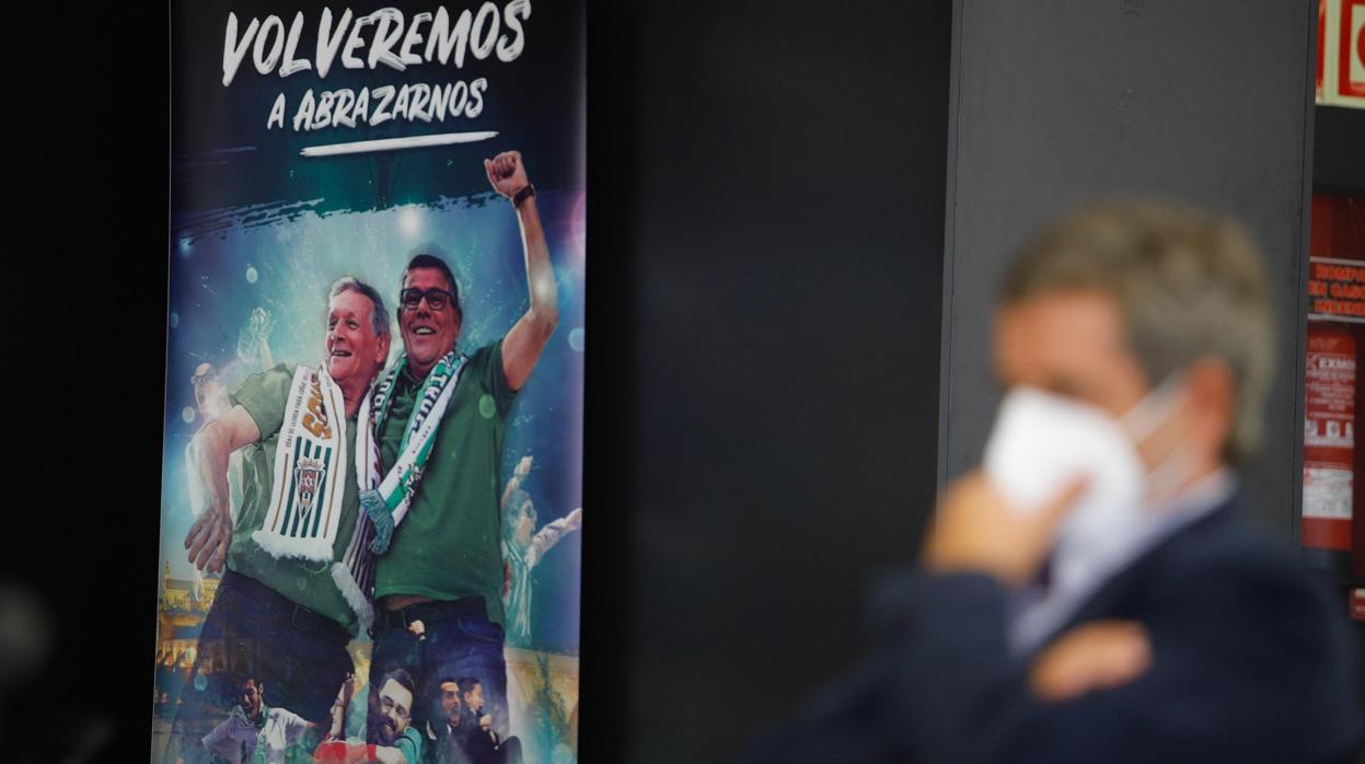 El presidente del Córdoba CF SAD, Carlos González, y el cartel de la campaña de abonados, de fondo