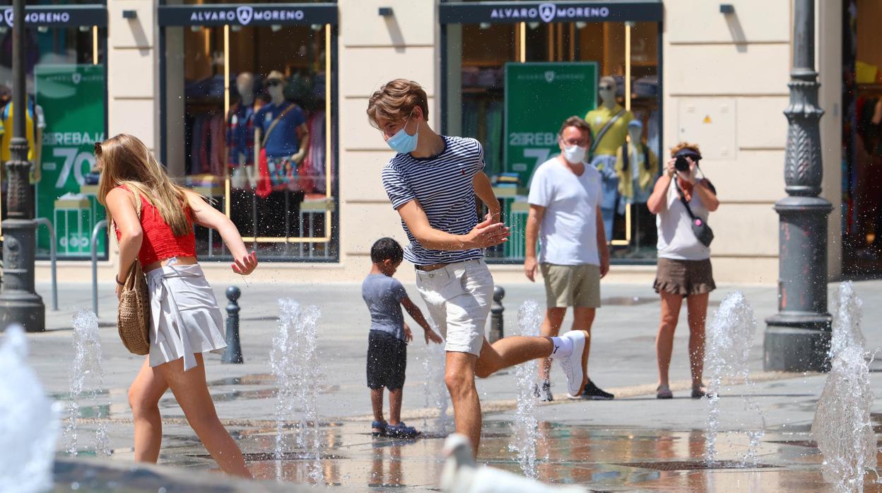 Una pareja juega con los chorros de la plaza de Las Tendillas