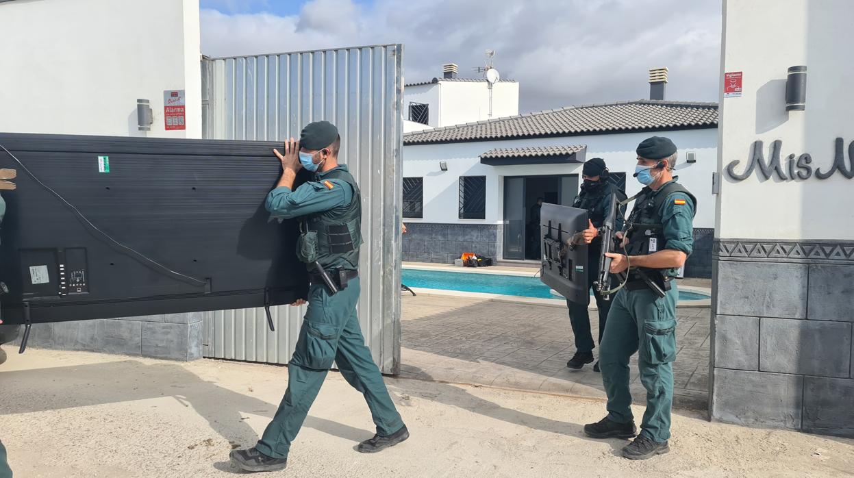 Agentes transportan varias televisiones intervenidas en el registro de La Línea