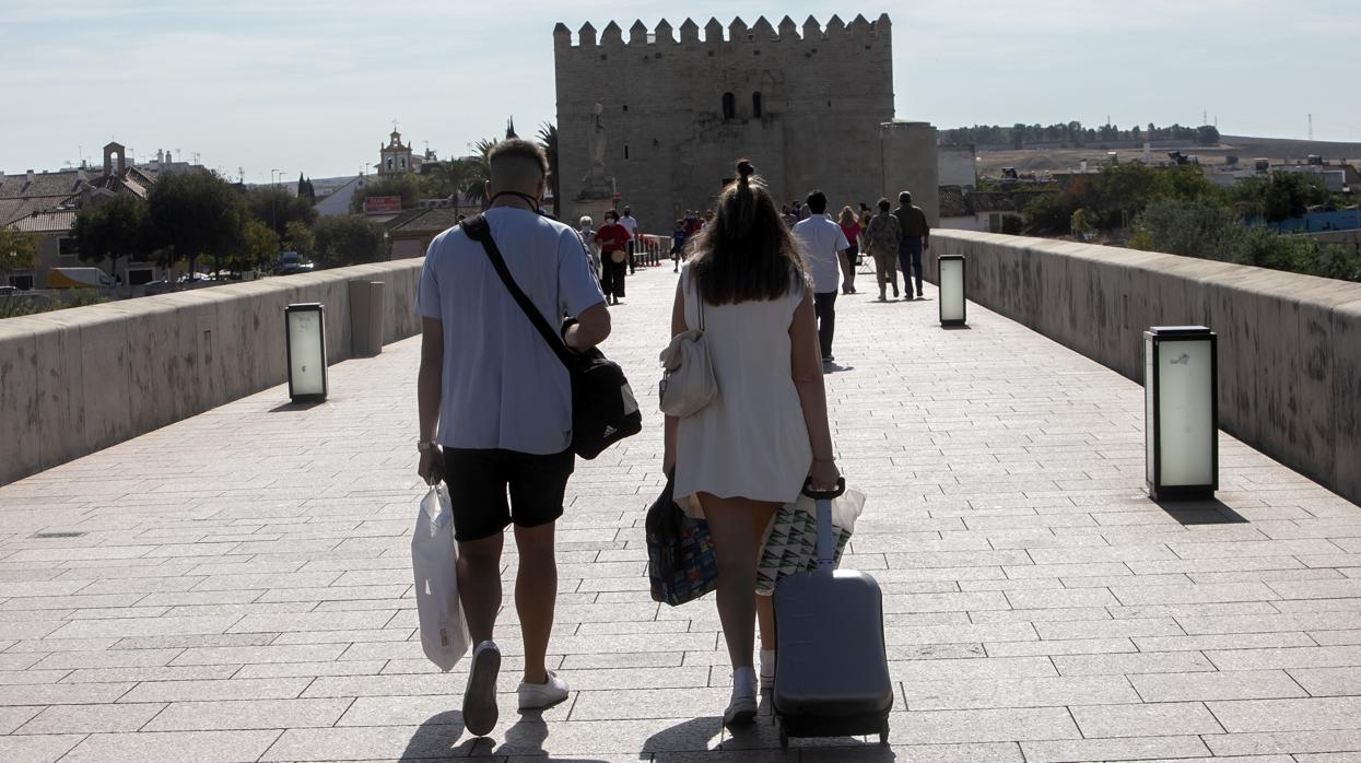 Una pareja de turistas pasa por el Puente Romano