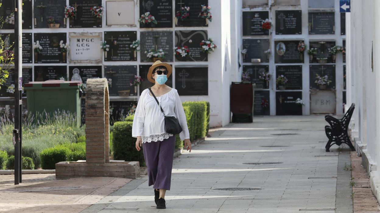 Una mujer con mascarilla y sombrero en el cementerio de San Rafael