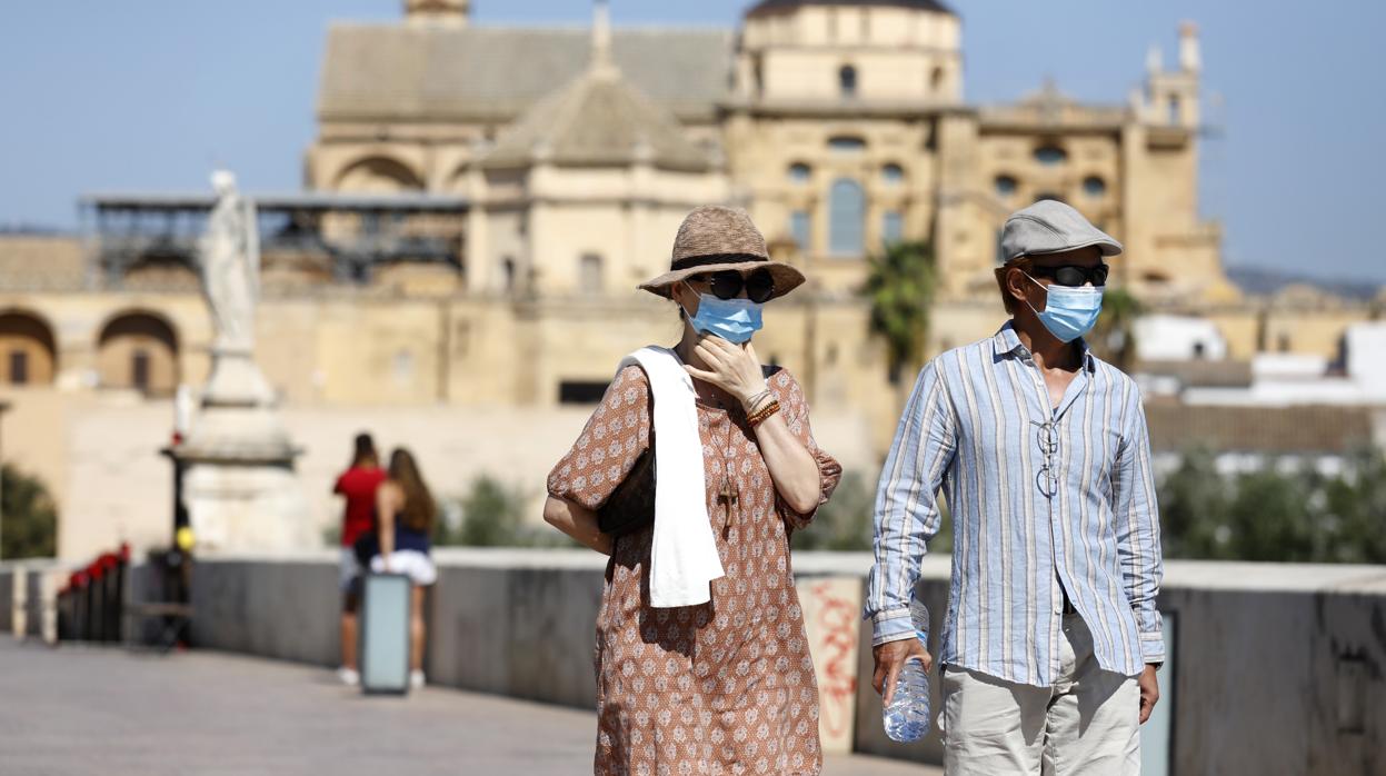 Dos turistas pasean en septiembre por el Puente Romano de Córdoba