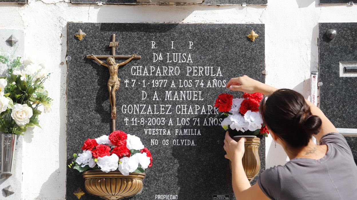 Una mujer coloca flores en un nicho