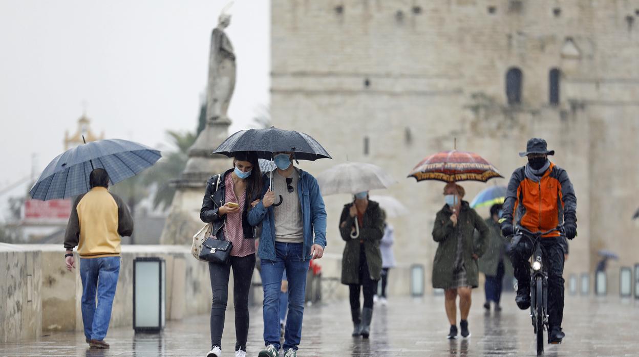 Peatones cruzan el Puente Romano bajo la mirada de San Rafael