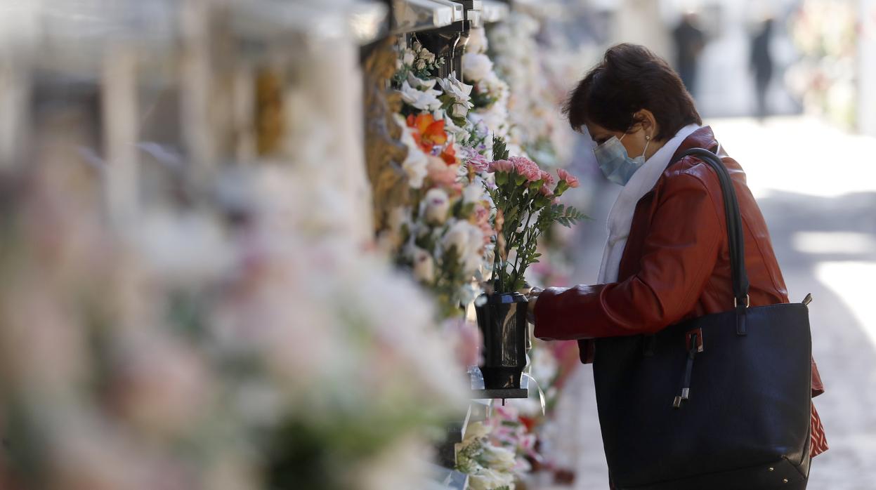 Una mujer pone flores en un nicho el cementerio de San Rafael