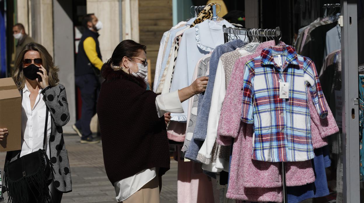 Una cliente mira la ropa colgada en una tienda textil de Córdoba