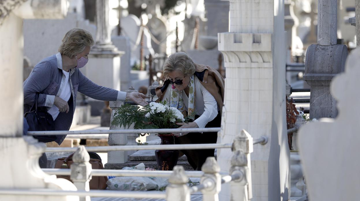 Dos mujeres colocan flores en una tumba del cementerio de la Salud