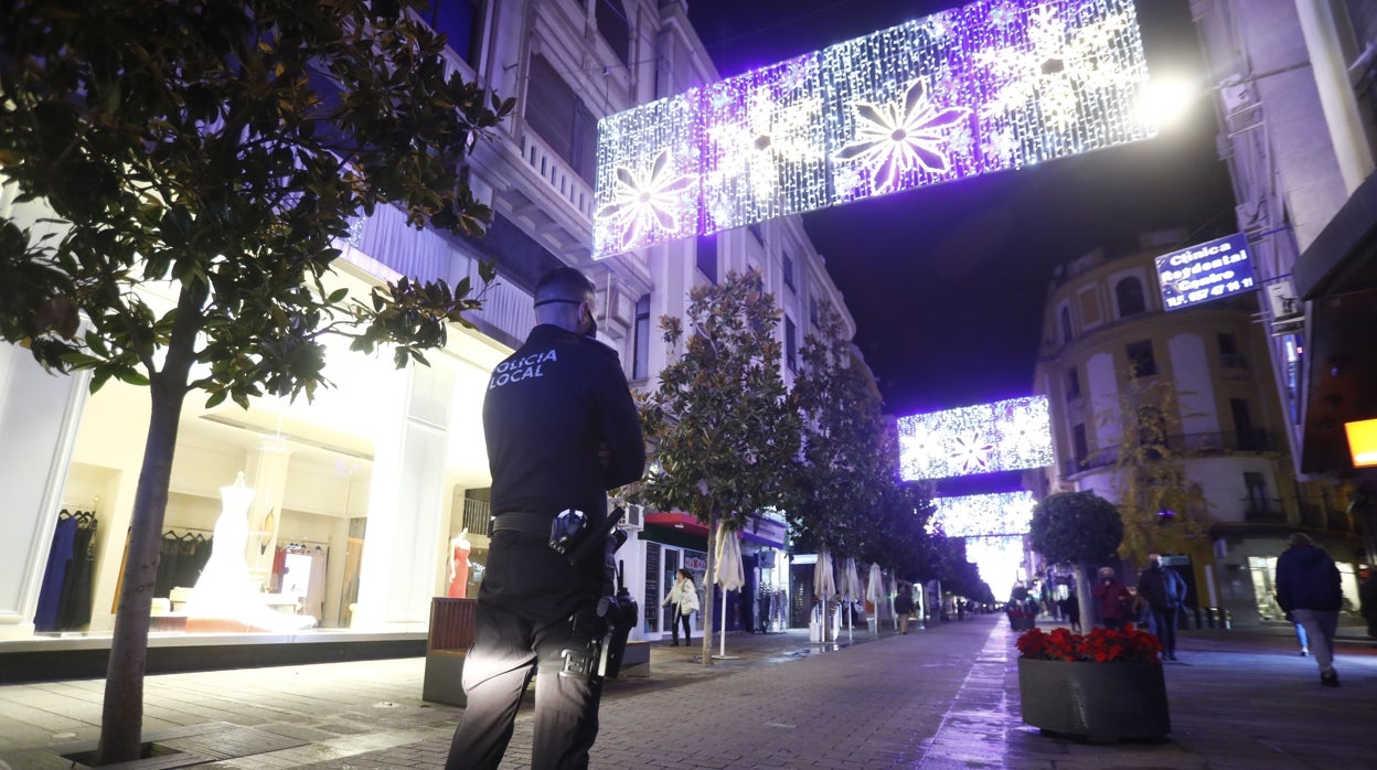 Un policía local vigila una calle iluminada con motivos navideños en Córdoba