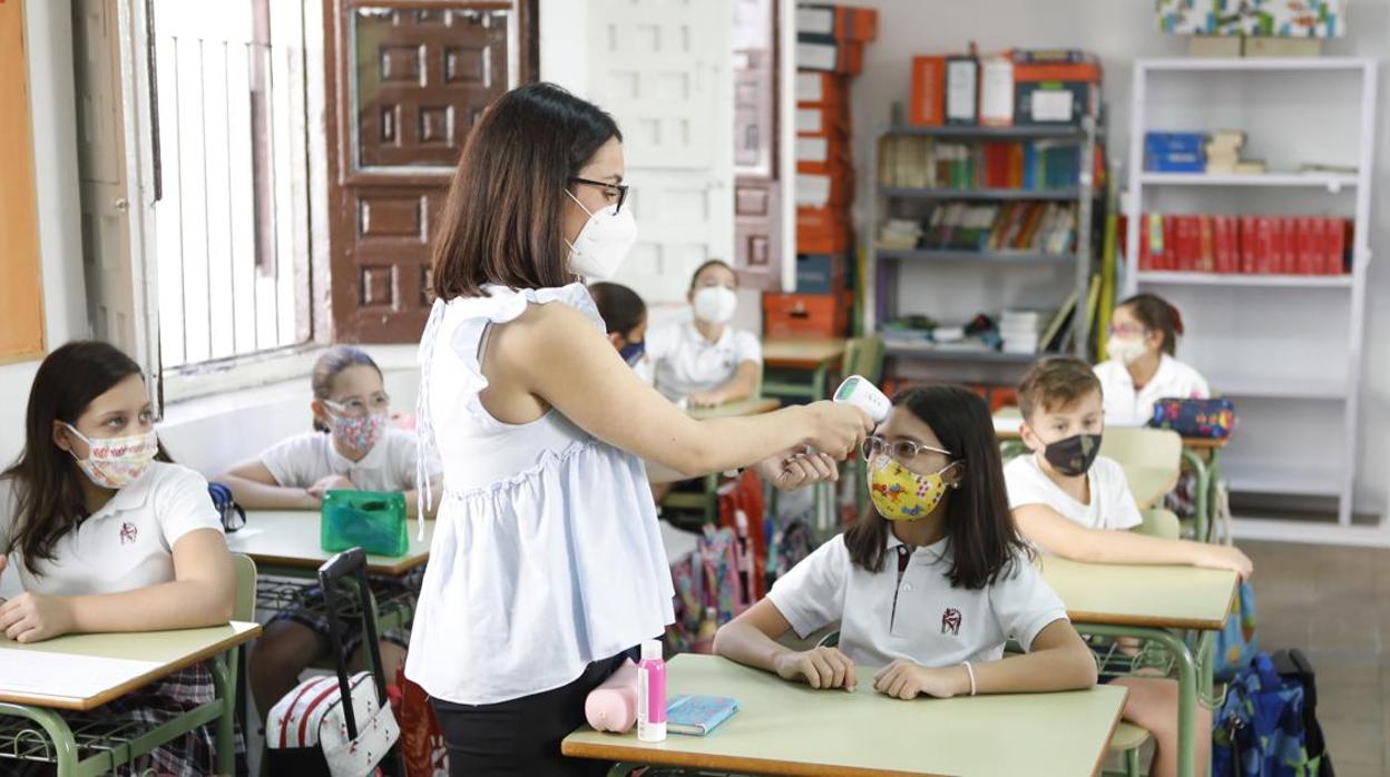 Una docente toma la temperatura a una alumna en una imagen de archivo