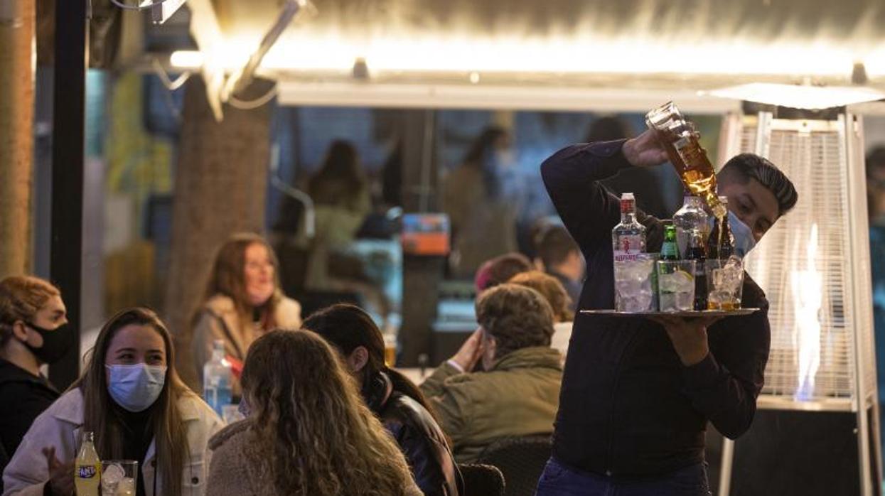 Un camarero sirve bebidas alcohólicas en un bar después de las 8 de la tarde