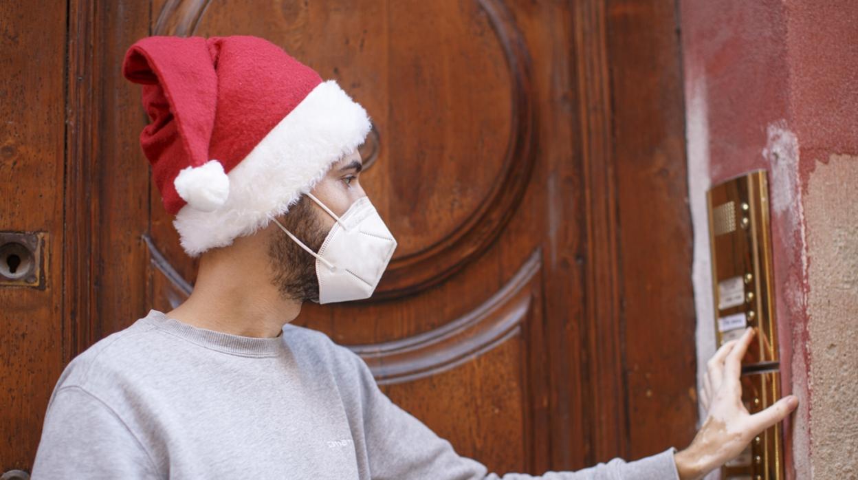 Un joven con mascarilla y gorro de Papa Noel