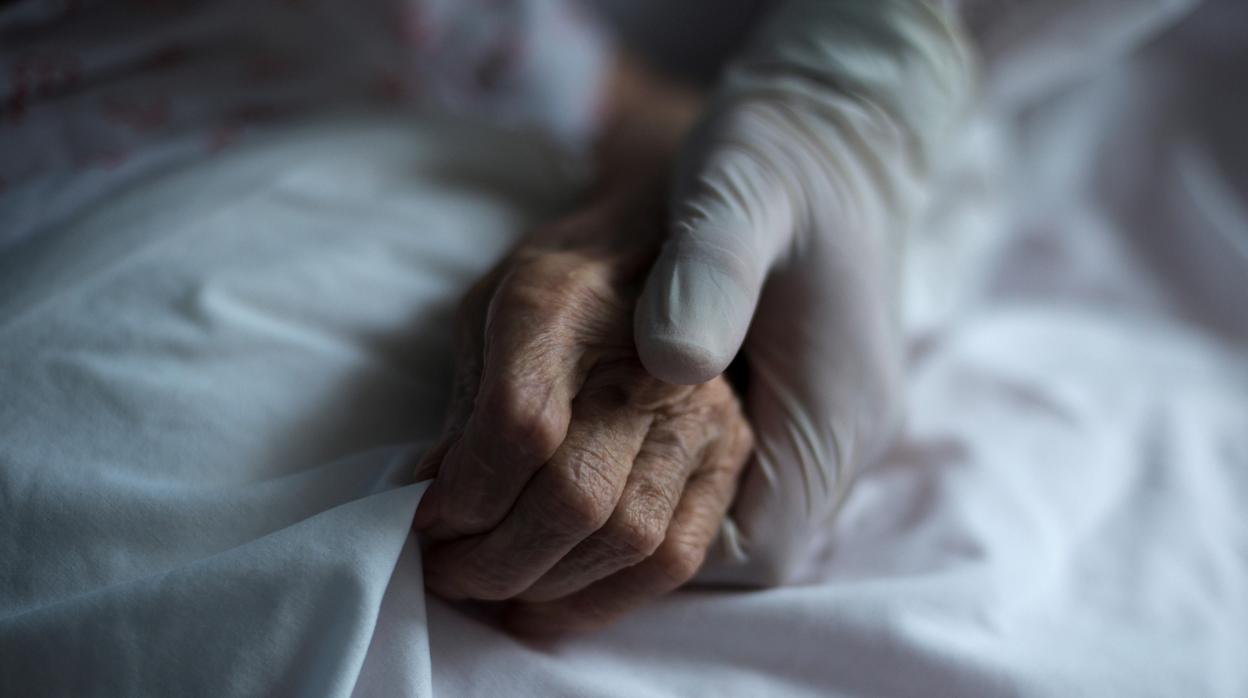 Un sanitario coge la mano de un mayor en una residencia de ancianos