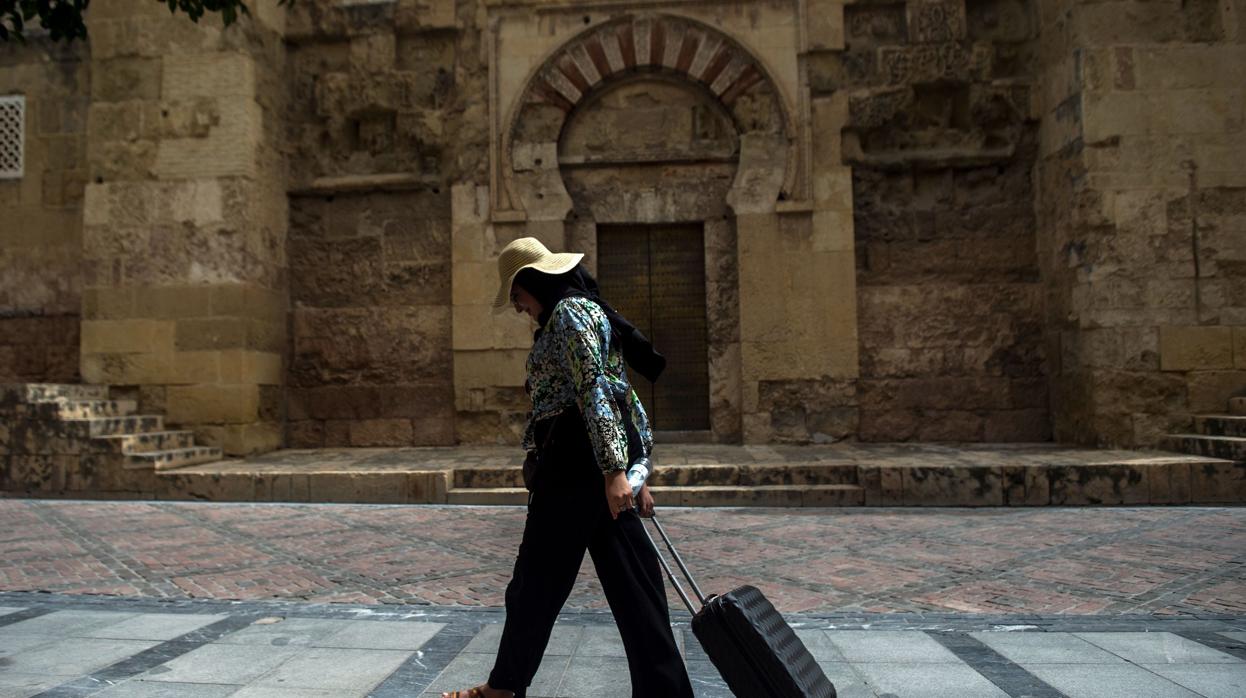 Una turista pasa con su maleta delante de la Mezquita-Catedral de Córdoba