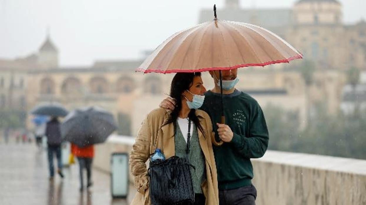 Una pareja bajo la lluvia pasando por el Puente Romano