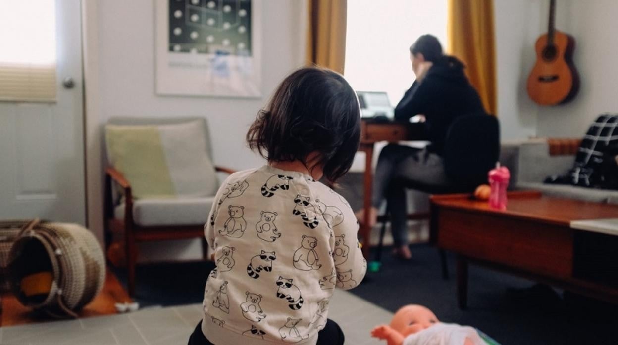 Una niña juega mientras su madre trabaja con un ordenador