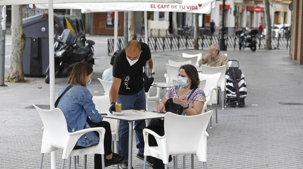 Un camarero atiende a dos clientas en un bar junto a la plaza de Colón