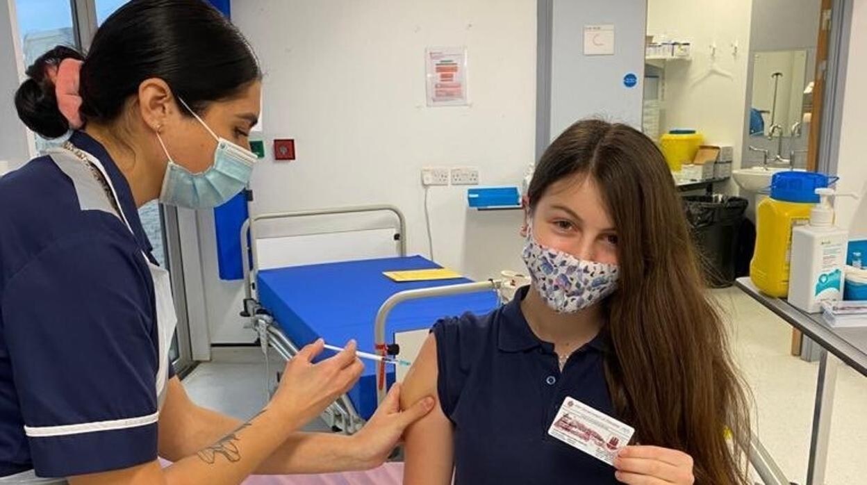 Una adolescente gibraltareña recibe la segunda dosis de la vacuna y muestra su certificado Covid
