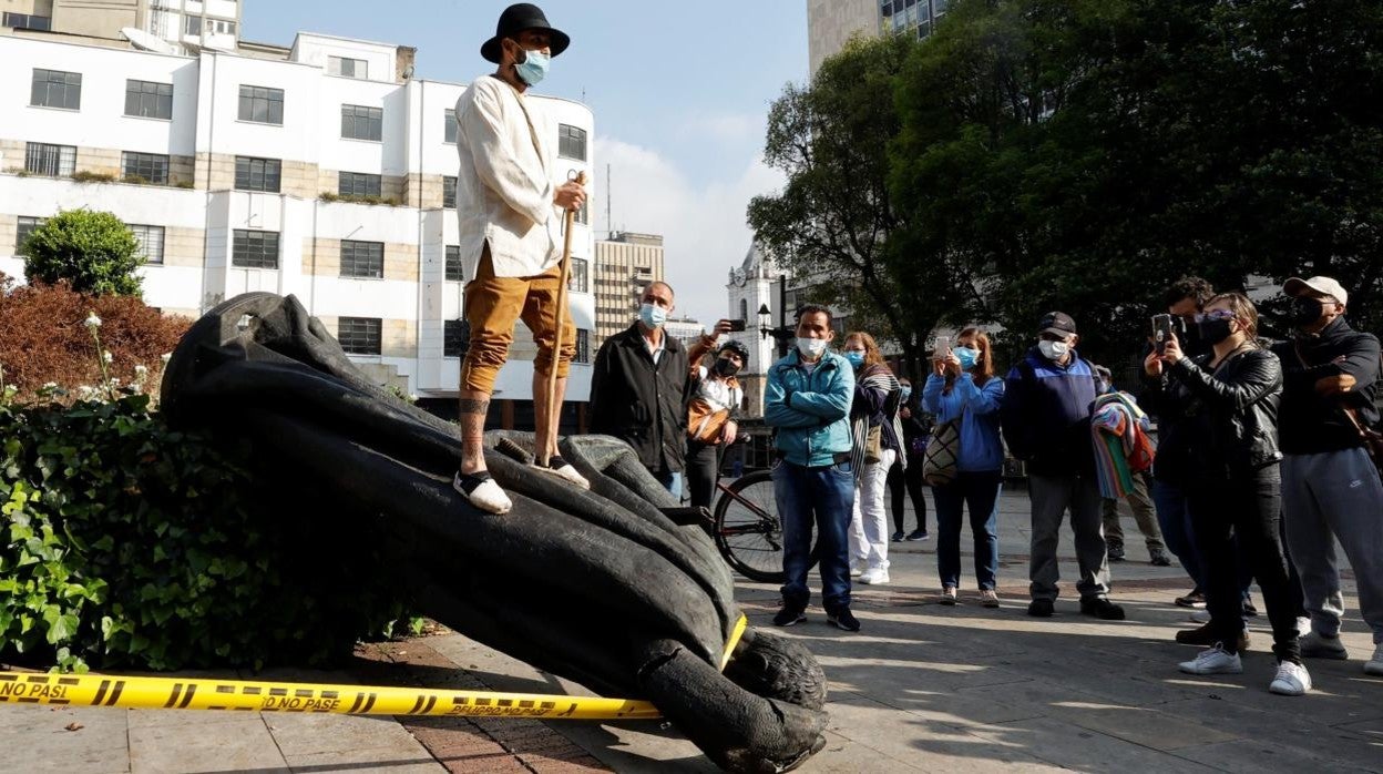 Un indígena se sube encima de la estatua de Jiménez de Quesada, tras su derribo