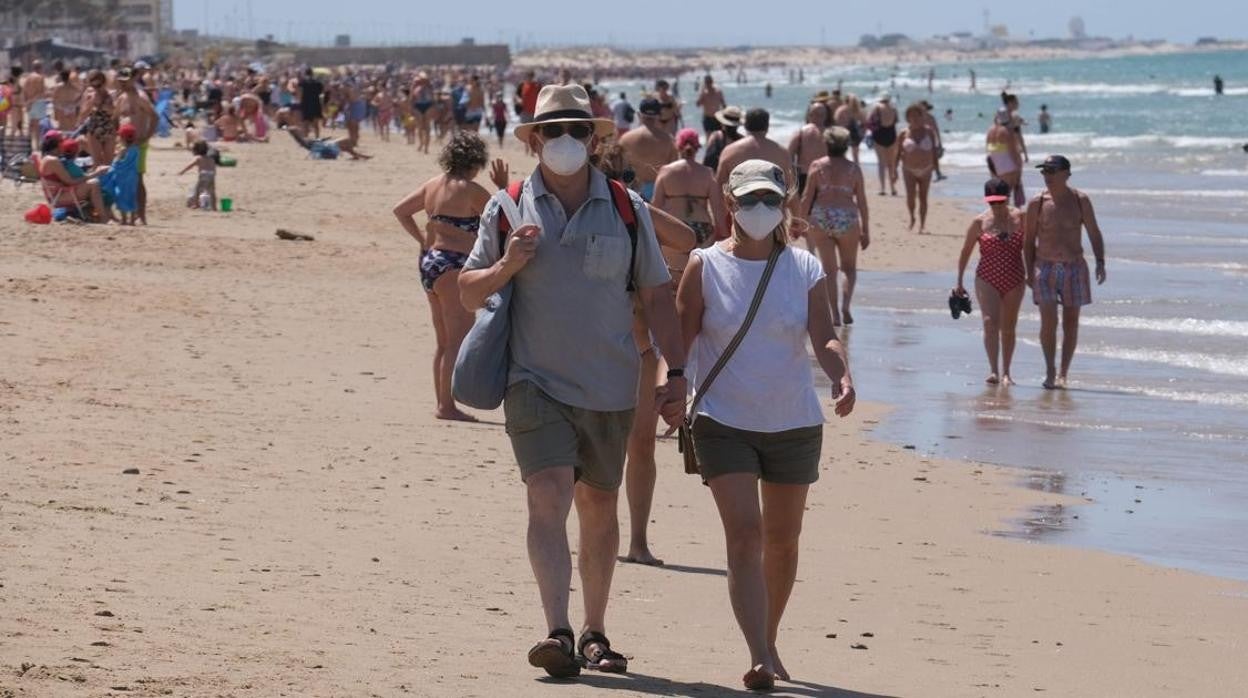 Turistas en la playa con la mascarilla puesta en una imagen de archivo